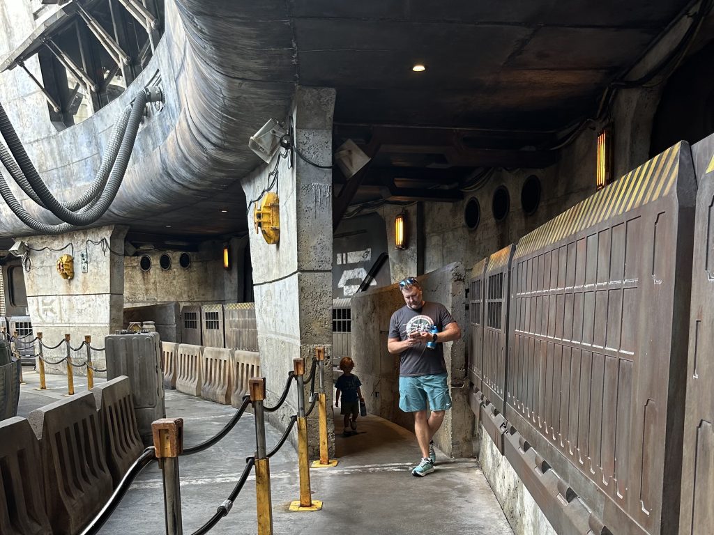 A man and a young boy in shadows getting into line at Disney World