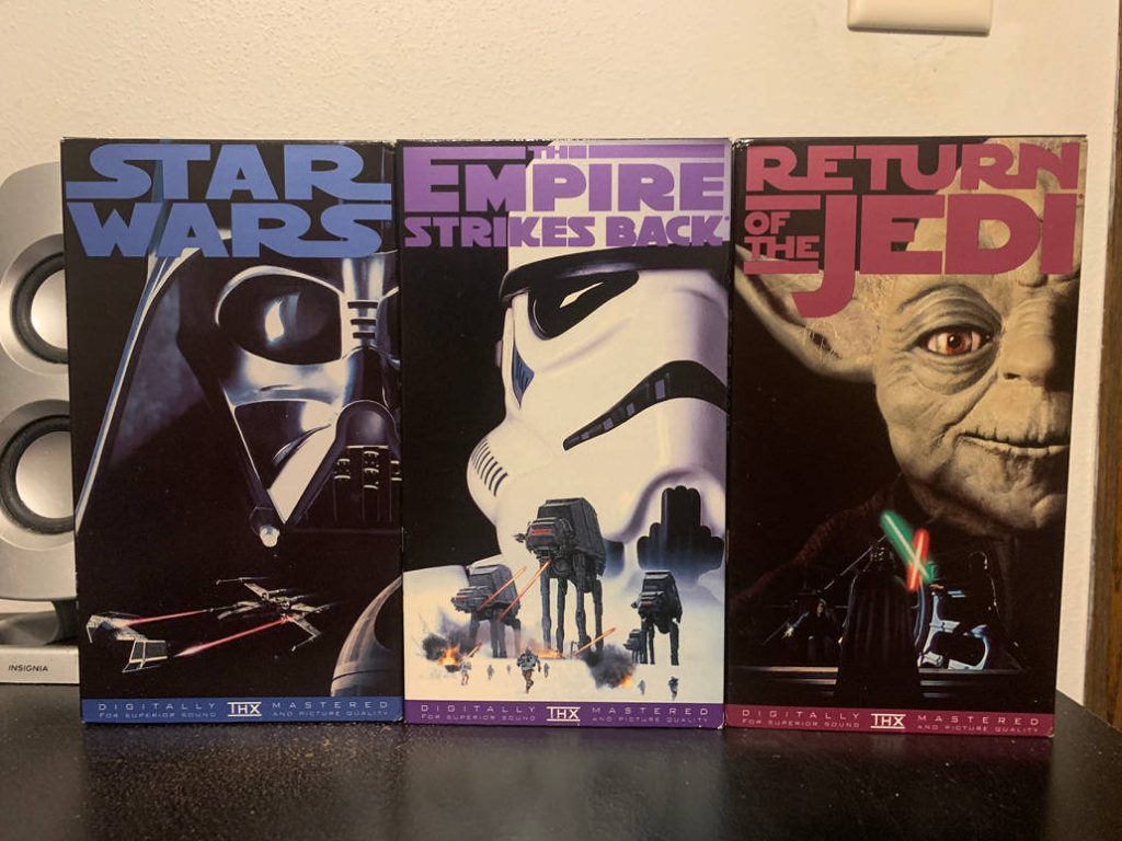 Three VHS tapes of Star Wars movies on a black surface.