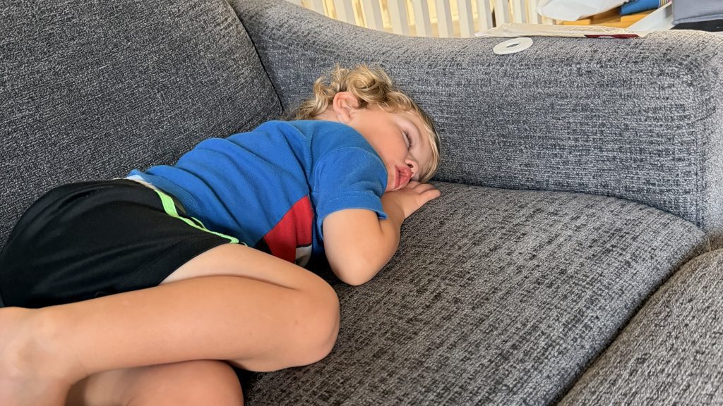 A young child asleep on a grey couch