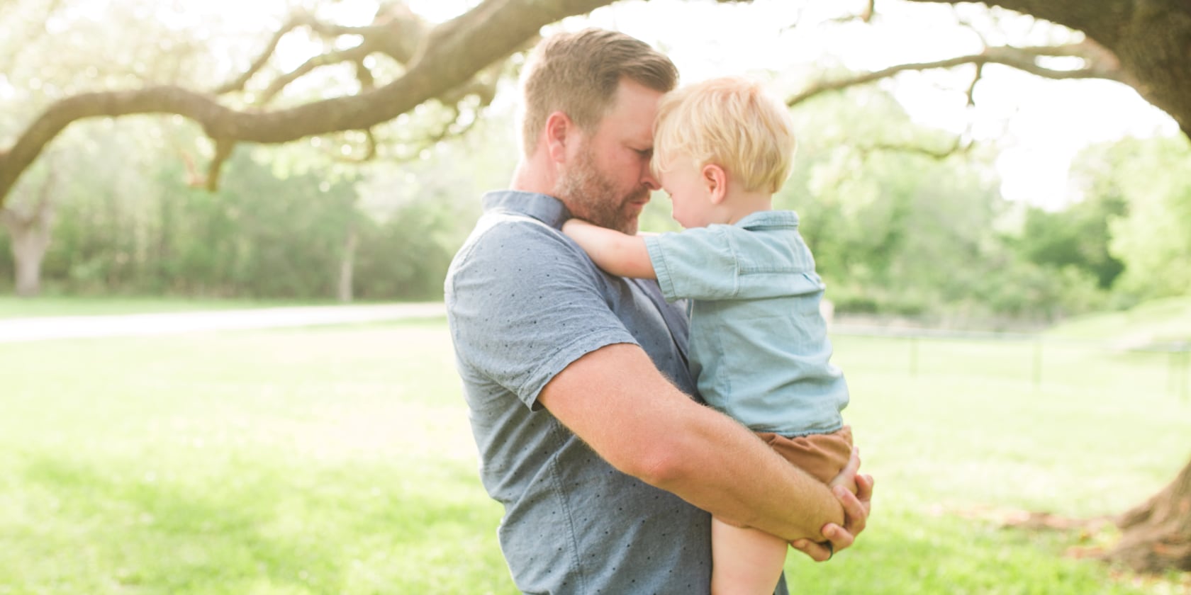 a stay-at-home dad and his son with trees in the background