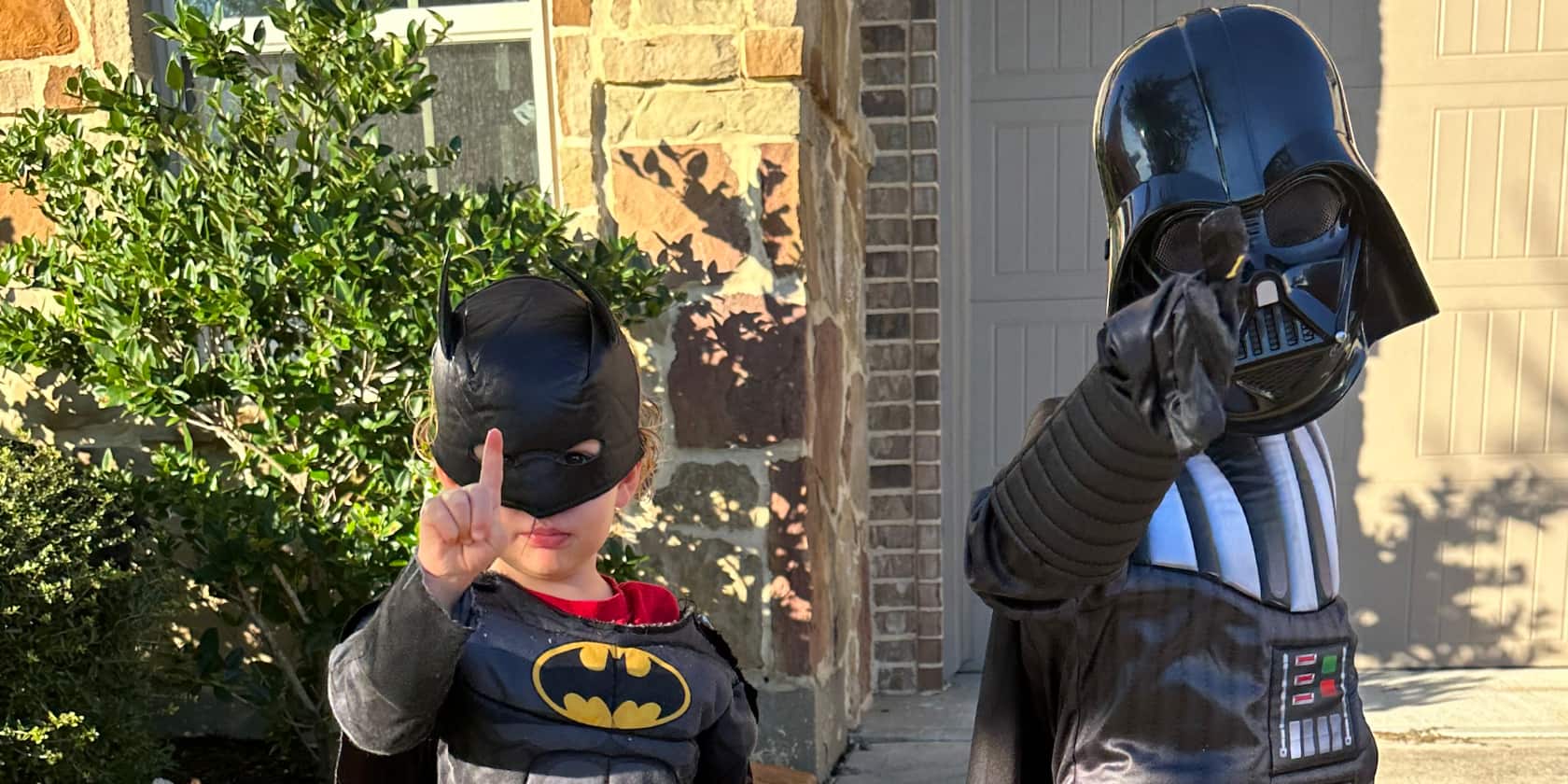 Two young boys in costumes. One is batman and one is Darth Vader