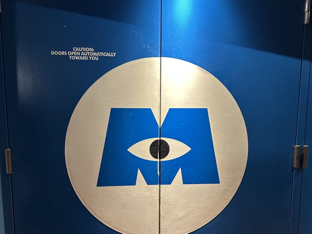 Conquering Disney World— My First Visit in Almost 40 Years 27 a door with a blue M in the middle. There is an eye in the middle of the M