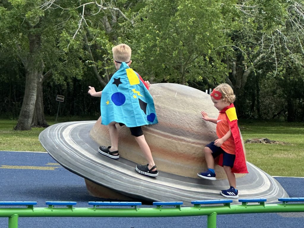 Writing In The Margins - How I Find Time for Writing As A Stay-at-Home Dad 3 Two kids in capes playing on a planet shaped playground.