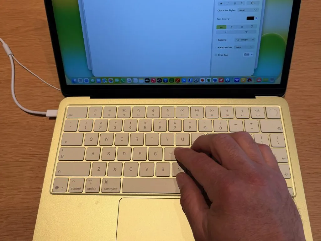 A hand typing on the MacBook Neo